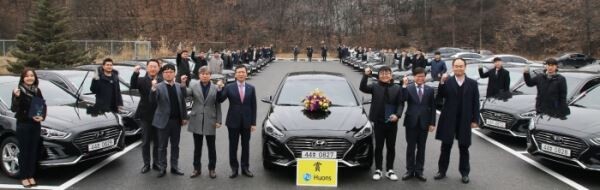 ▲ 휴온스글로벌 윤성태 부회장(중앙에서 왼쪽), 휴온스 엄기안 대표(중앙에서 오른쪽 두번째) 이하 임원들과 우수 영업사원 34인이 포상 차량 앞에서 기념촬영을 하고 있다. [사진=휴온스]