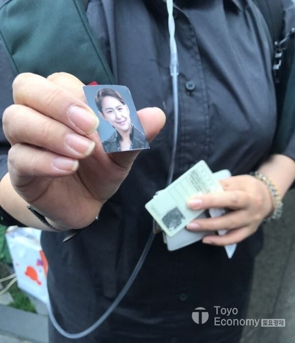 ▲가습기살균제 피해자들이 2일 서울 여의도 옥시레킷벤키저 사옥 앞에 분향소를 설치하고, 정부와 옥시 등 가해기업을 대상으로 피해 해결을 촉구하는 무기한 농성에 돌입했다. 이날 참석한 조순미 천식인정자 권리찾기 대표가 취재진에 영정사진을 보여주는 모습. [사진=김자혜 기자]