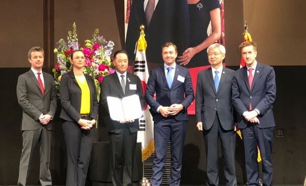 ▲칼스버그 그룹 아나스 루드 욘슨 부사장(왼쪽에서 네번째)과 ㈜골든블루 김동욱 대표(왼쪽에서 세번째)가 MOU 협약서를 들고 기념 사진을 촬영하고 있다. [사진=골든블루]